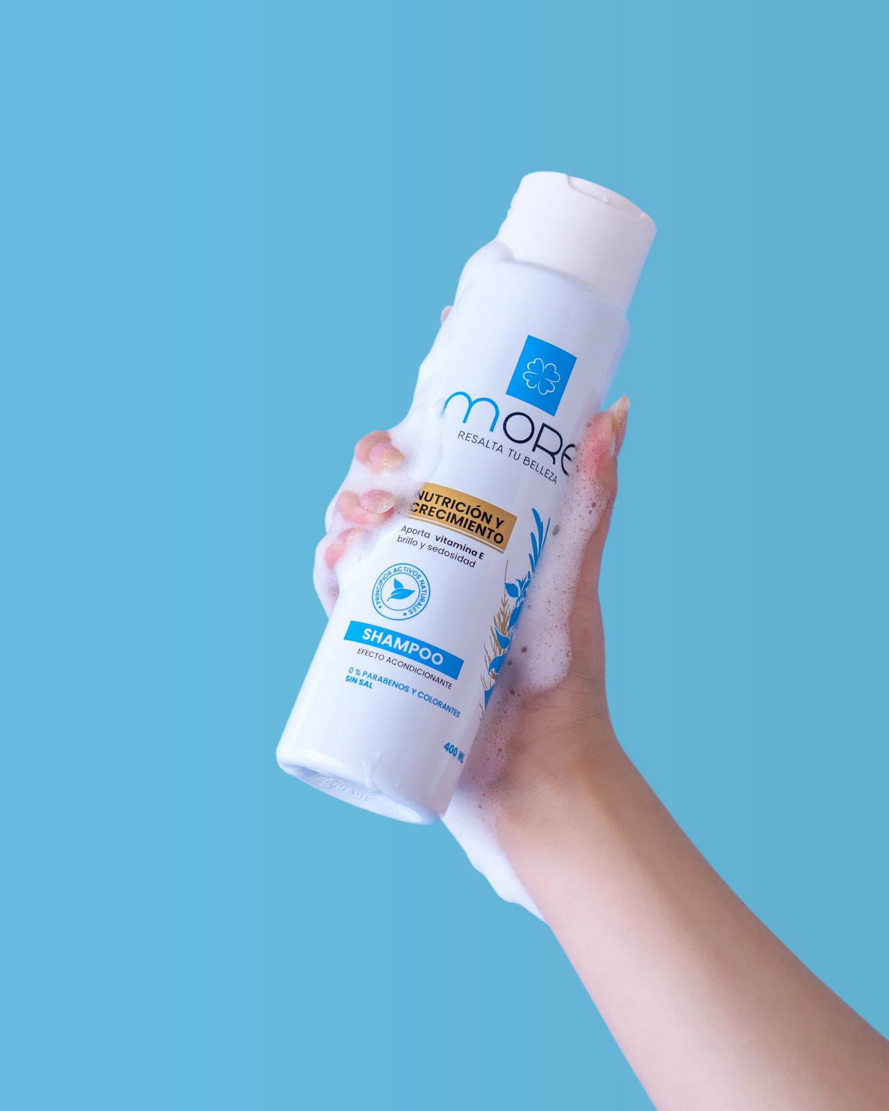 Mano sosteniendo el shampoo MORE de 400 ml con espuma